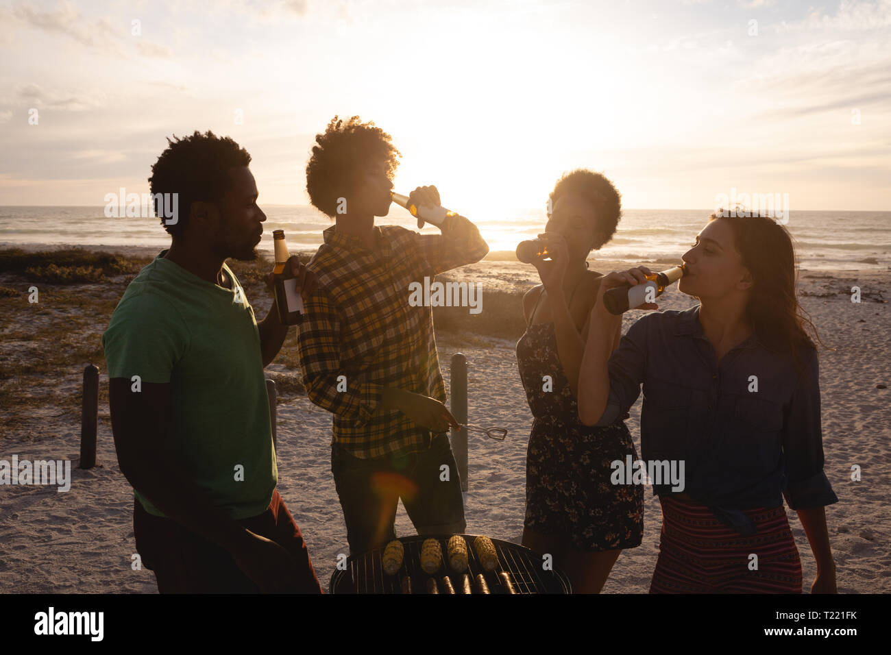 Un piccolo gruppo di amici a bere birra insieme a beach Foto Stock