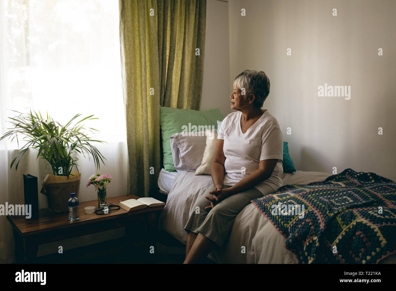 Senior donna seduta sul letto al momento del pensionamento home Foto Stock