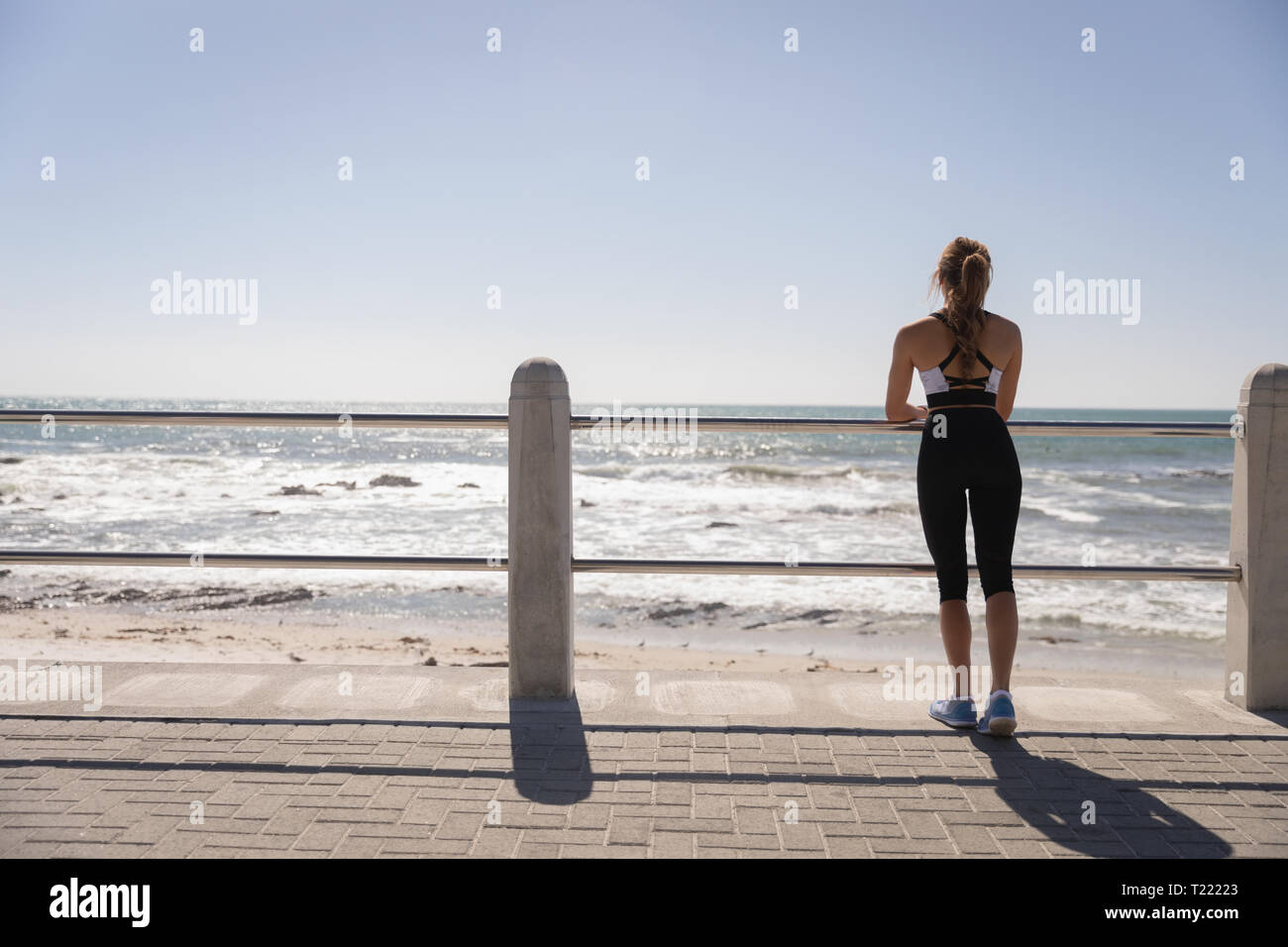 Bella donna in piedi vicino al mare a promenade in una giornata di sole Foto Stock