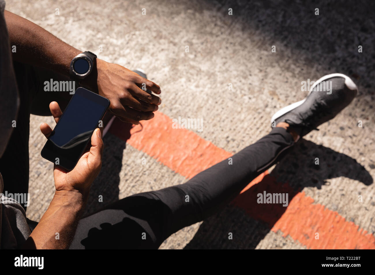 Uomo che utilizza il telefono cellulare mentre vi rilassate sulla strada Foto Stock