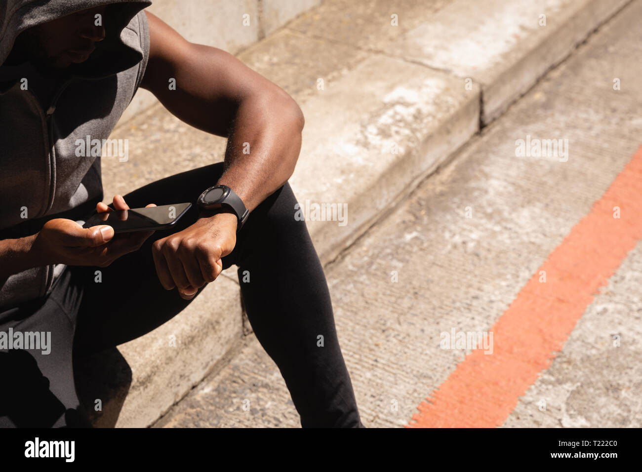 Uomo che utilizza il telefono cellulare mentre vi rilassate sulla strada al lato a piedi Foto Stock