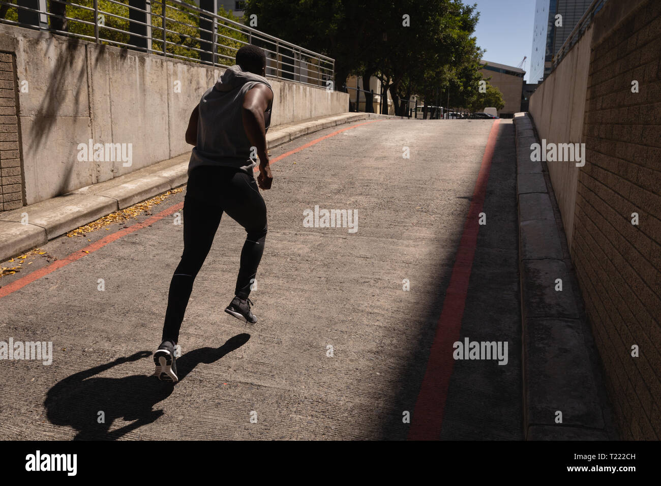 Uomo che corre dalla strada in una giornata di sole Foto Stock