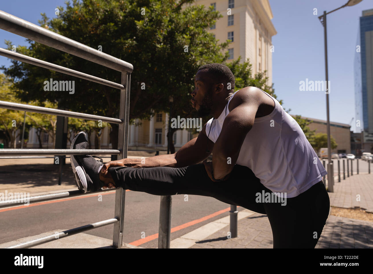 L'uomo facendo stretching esercitare contro la ringhiera di protezione Foto Stock