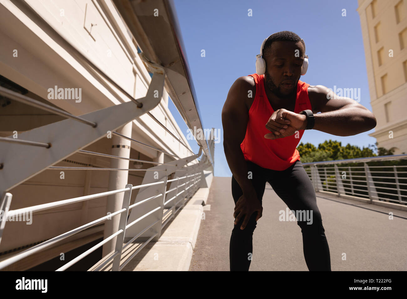 Uomo che guarda un orologio intelligente mentre vi rilassate sul ponte Foto Stock