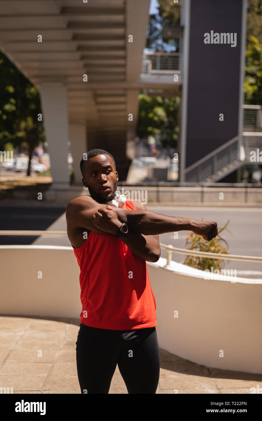 Man mano facendo esercizio di stiramento al marciapiede sotto il ponte Foto Stock