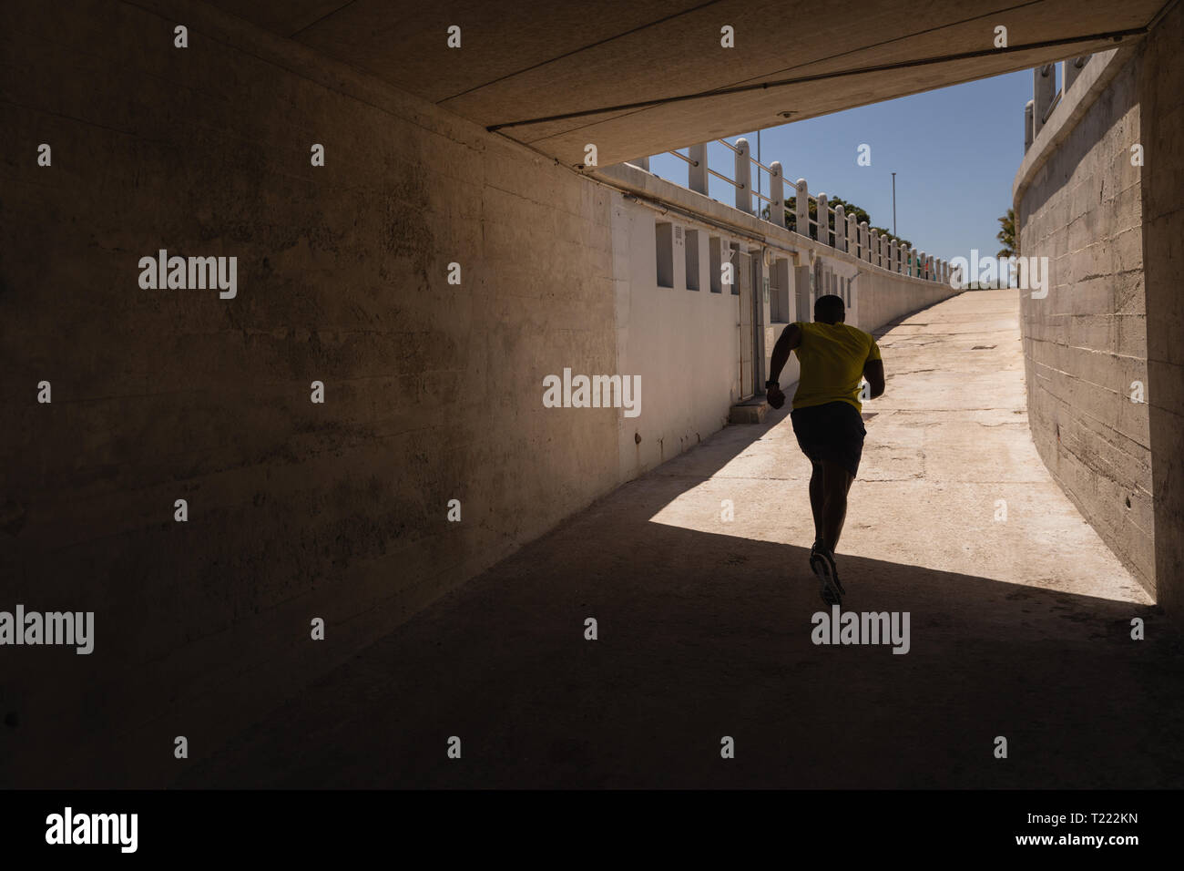 Uomo che corre sotto il ponte in una giornata di sole Foto Stock