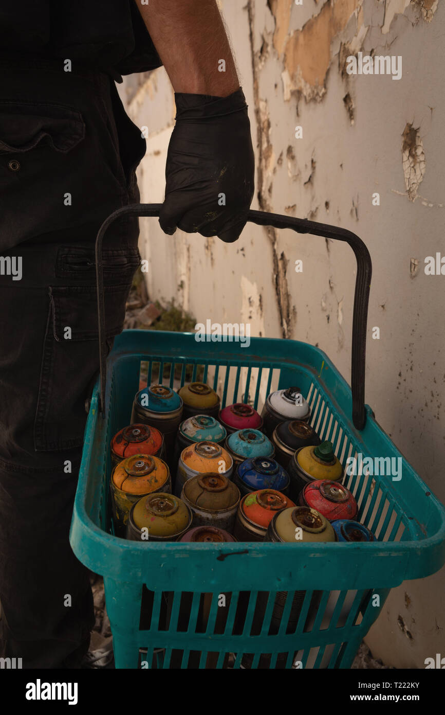 Artista di graffiti a piedi con cesto di vernice spray Foto Stock