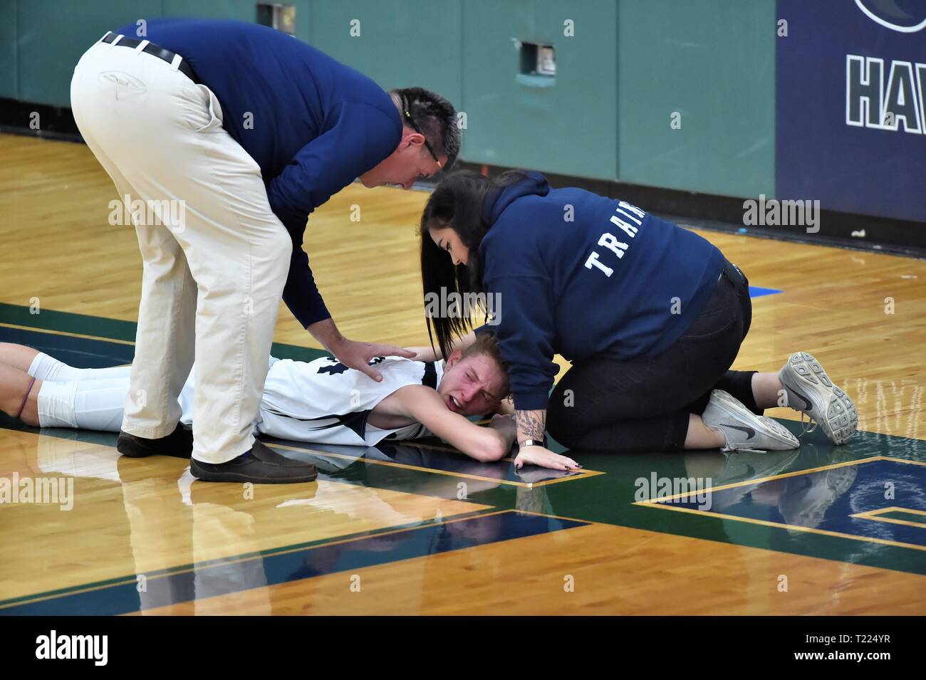Coach preparatore atletico tendono ad un giocatore ferito sul pavimento della palestra. Stati Uniti d'America. Foto Stock