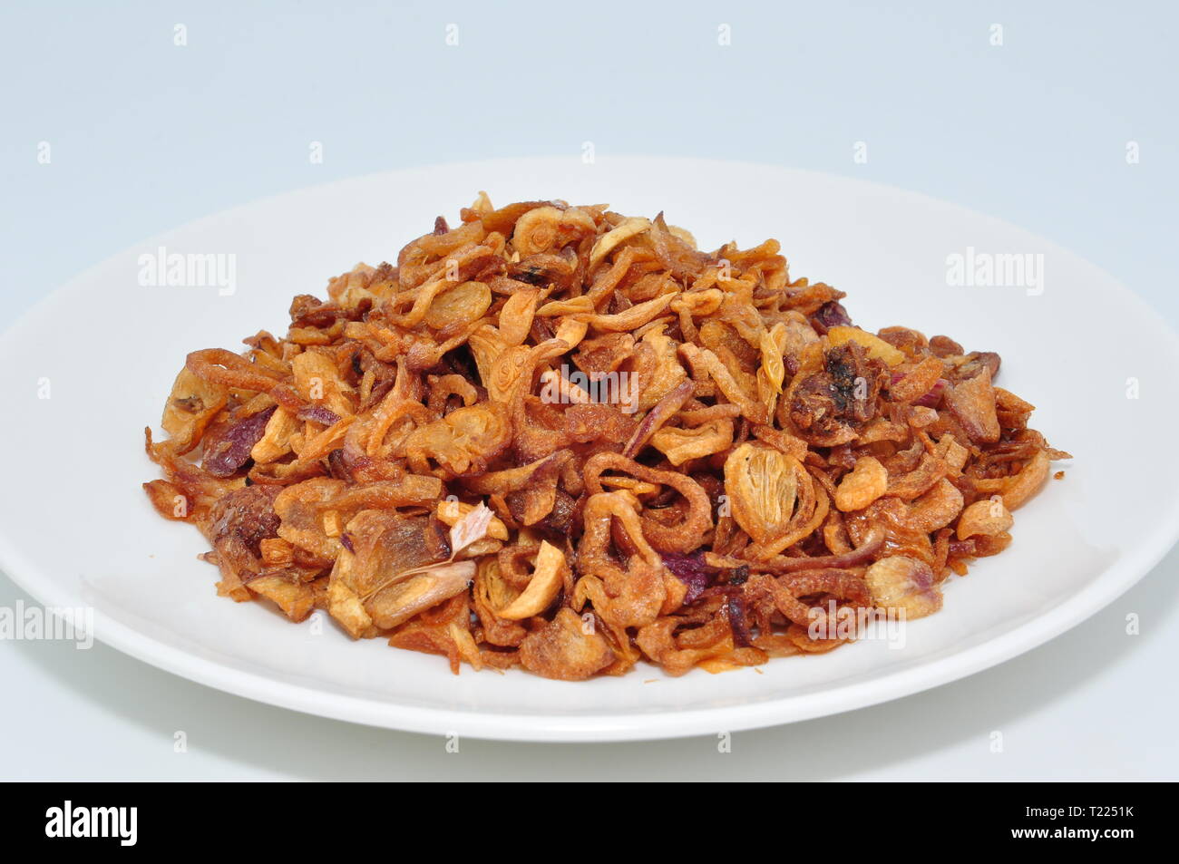 Fritti di scalogni per la guarnitura in ciotola bianco su sfondo bianco Foto Stock