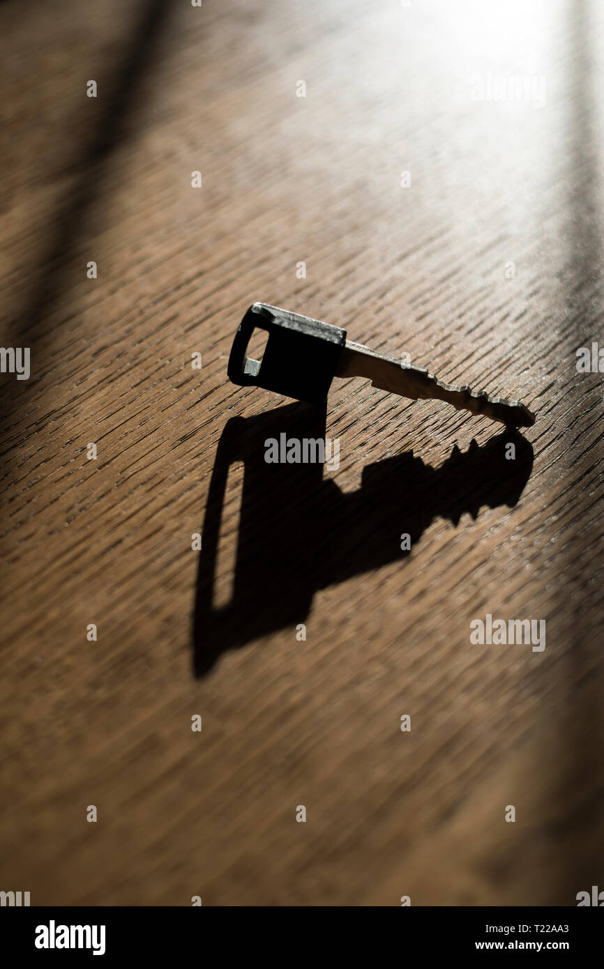Chiave auto getta un' ombra su un tavolo di legno. Foto Stock