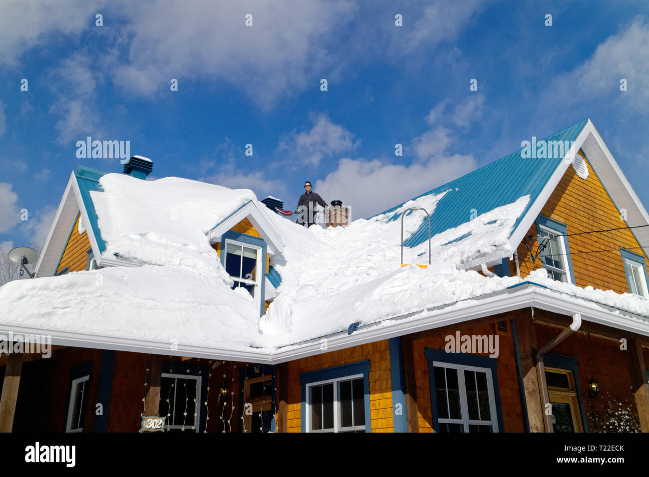 Un uomo sul tetto della sua casa la rimozione di neve in Quebec. Inverno del 2018-2019 ha visto molto forti nevicate Foto Stock