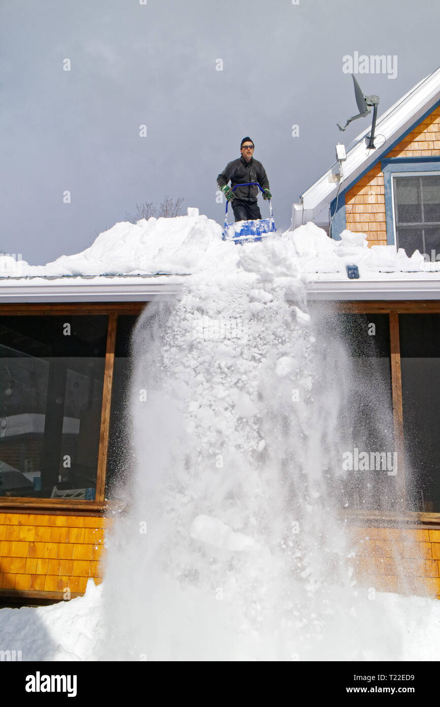 Un uomo sul tetto della sua casa la rimozione di neve in Quebec. Inverno del 2018-2019 ha visto molto forti nevicate Foto Stock