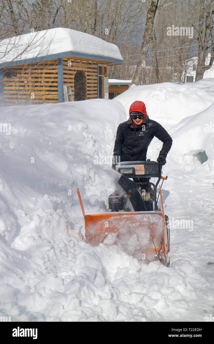 Una donna con un ventilatore di neve per cancellare la neve dal suo giardino in Quebec. Inverno 2018-2019 visto molto forte nevicata. Foto Stock