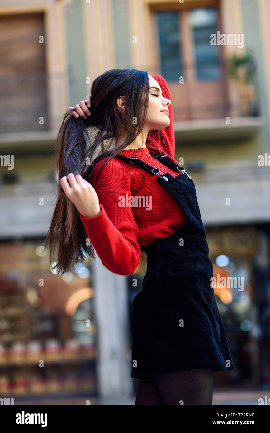 Moda giovane donna indossa maglia rossa pullover e cinturino nero vestito in città Foto Stock