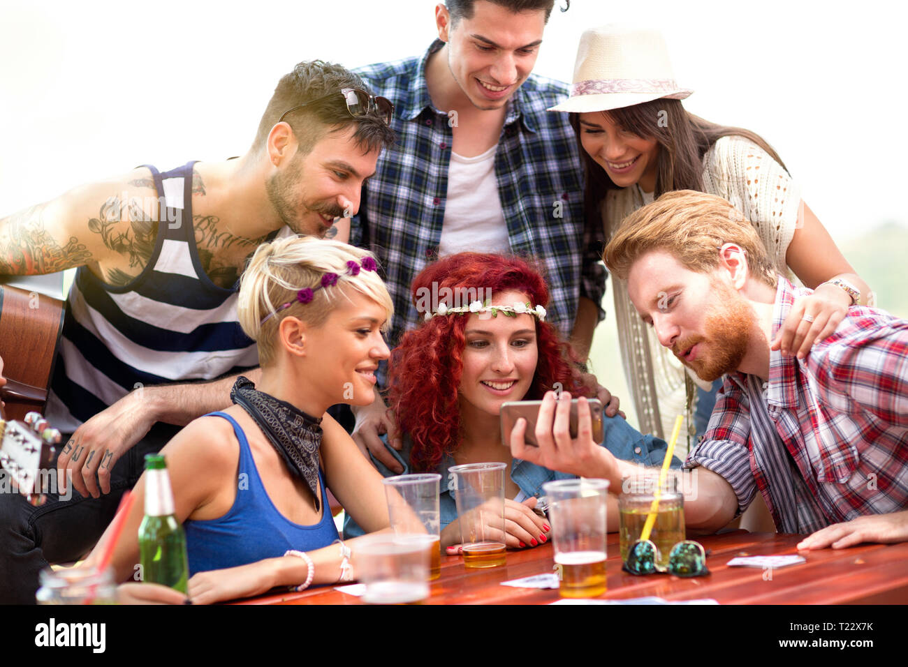 I ragazzi e le ragazze su picnic in natura il divertimento mentre guardi le foto a schermo del telefono cellulare Foto Stock