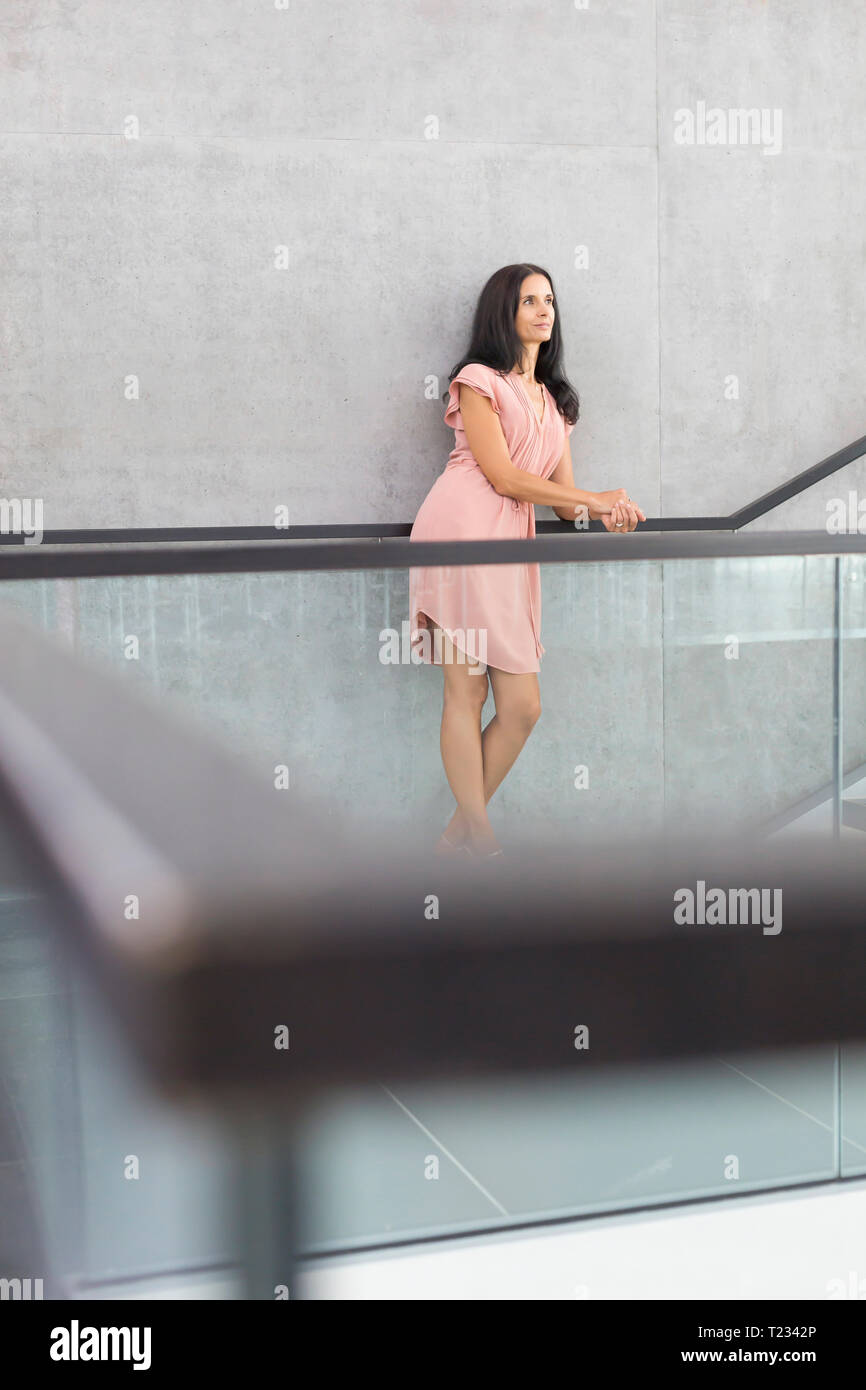 Donna matura rosa da indossare abiti estivi appoggiata sul parapetto Foto Stock