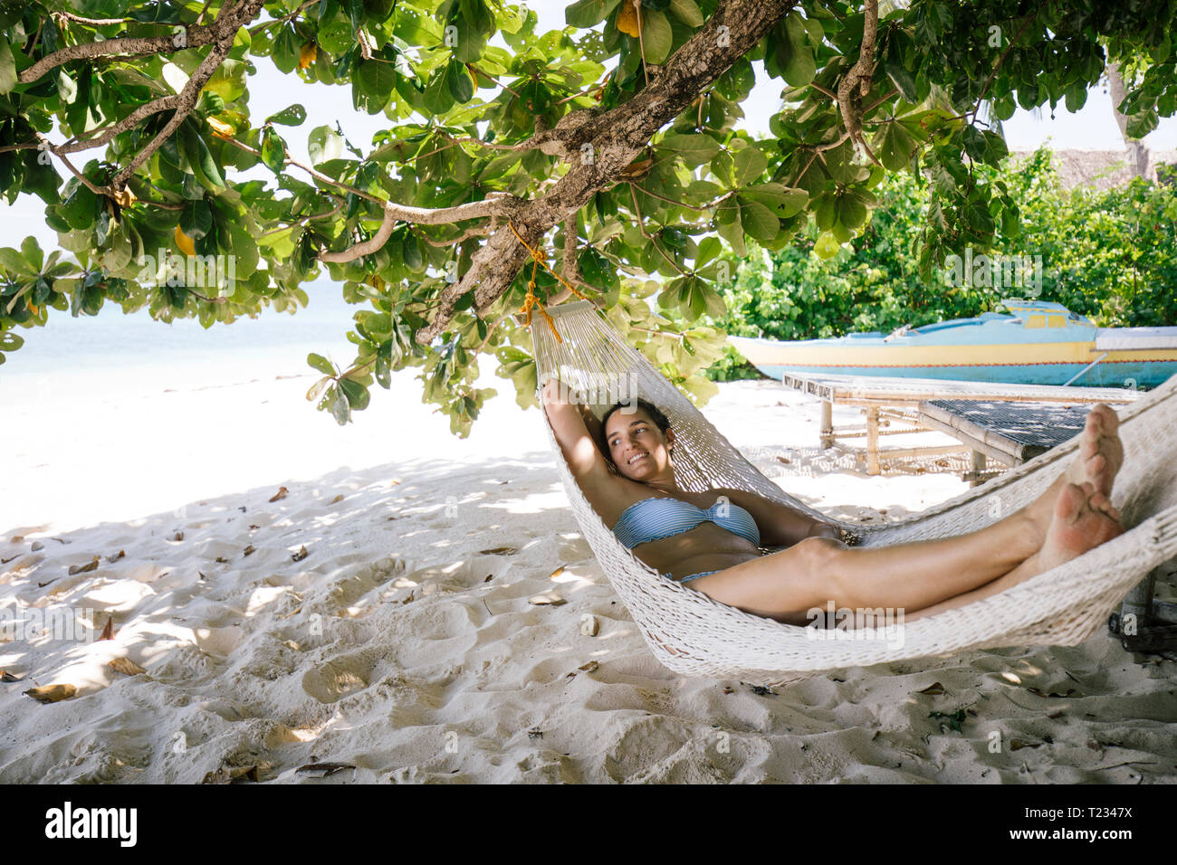 Filippine, Palawan Mangenguey Isola, Busuanga, donna giacente in amaca in spiaggia Foto Stock