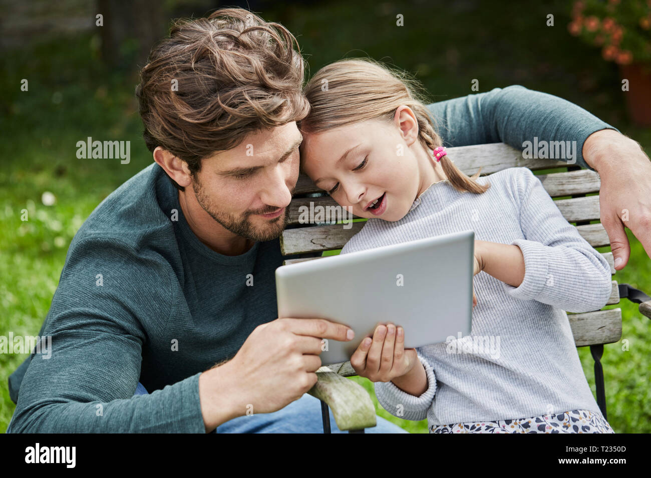 Padre e figlia utilizzando tablet insieme in giardino Foto Stock