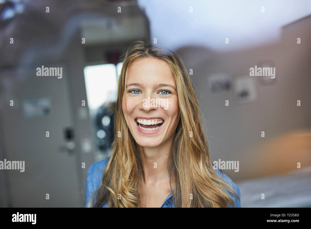 Ritratto di ridere giovane donna dietro il vetro di finestra Foto Stock