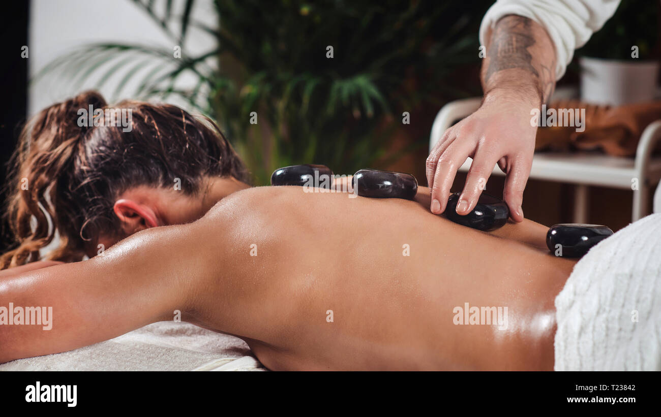 Giovane donna avente un massaggio con pietre calde. Foto Stock