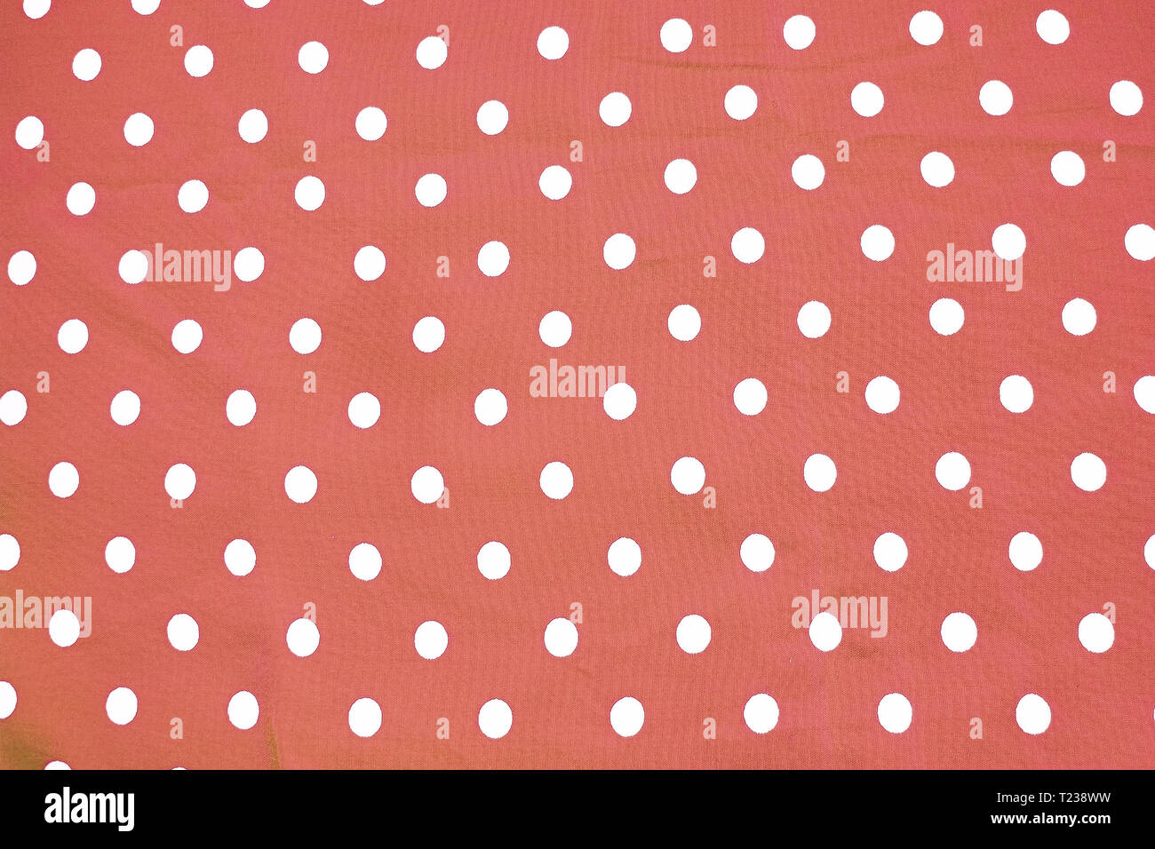 Il bianco e il rosso polka dot tessuto stampato divertimento romantico texture di sfondo virati al coralli viventi sfumature Foto Stock