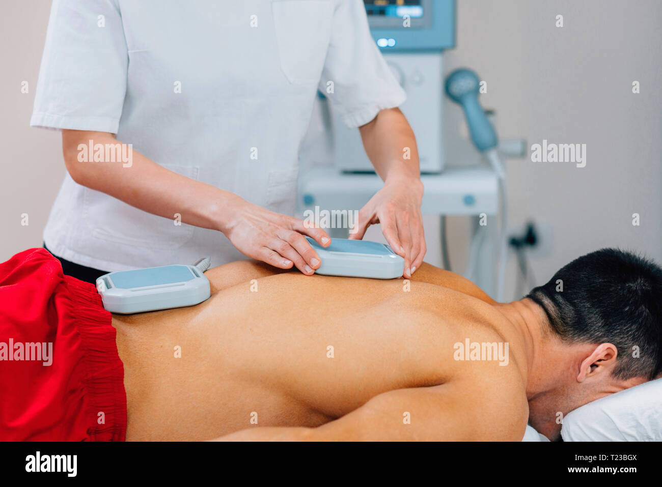 Magnetoterapia. Fisioterapista immissione magneti sulla schiena del paziente. Foto Stock