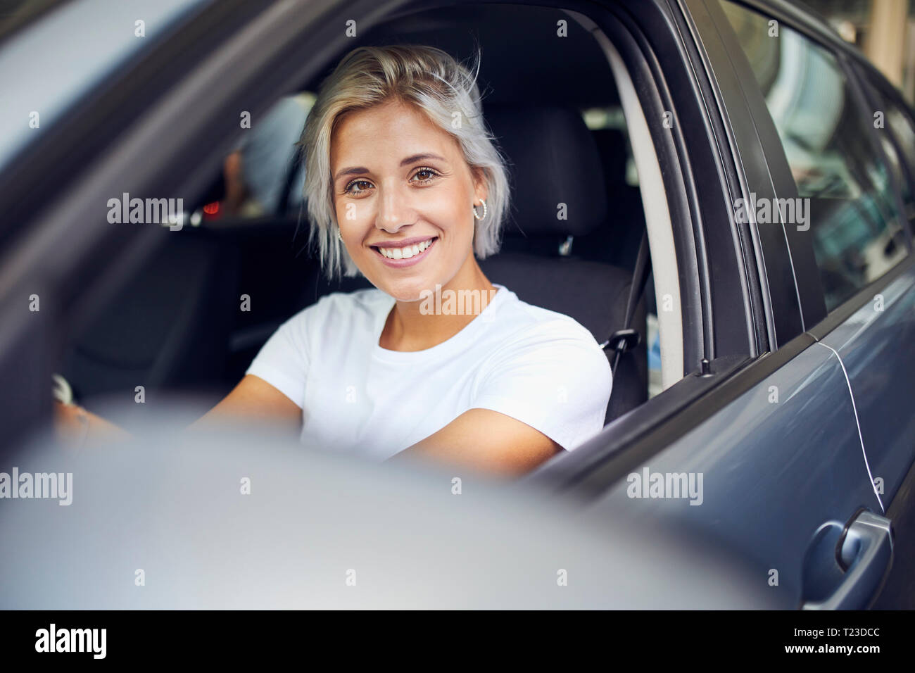 Giovane donna seduta nella sua auto Foto Stock