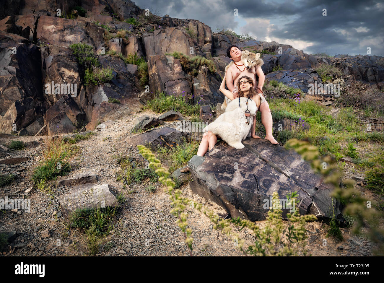 Primitivo persone vestite di pelle di animale in pietra con antica grotta disegno in montagna Foto Stock