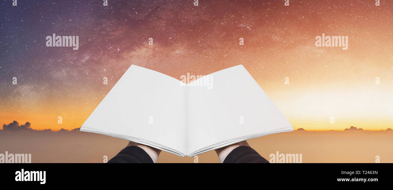 Mano azienda libro aperto, pagine vuote sulla colorata cielo stellato. Concetti di immaginazione, conoscenza, saggezza e istruzione Foto Stock