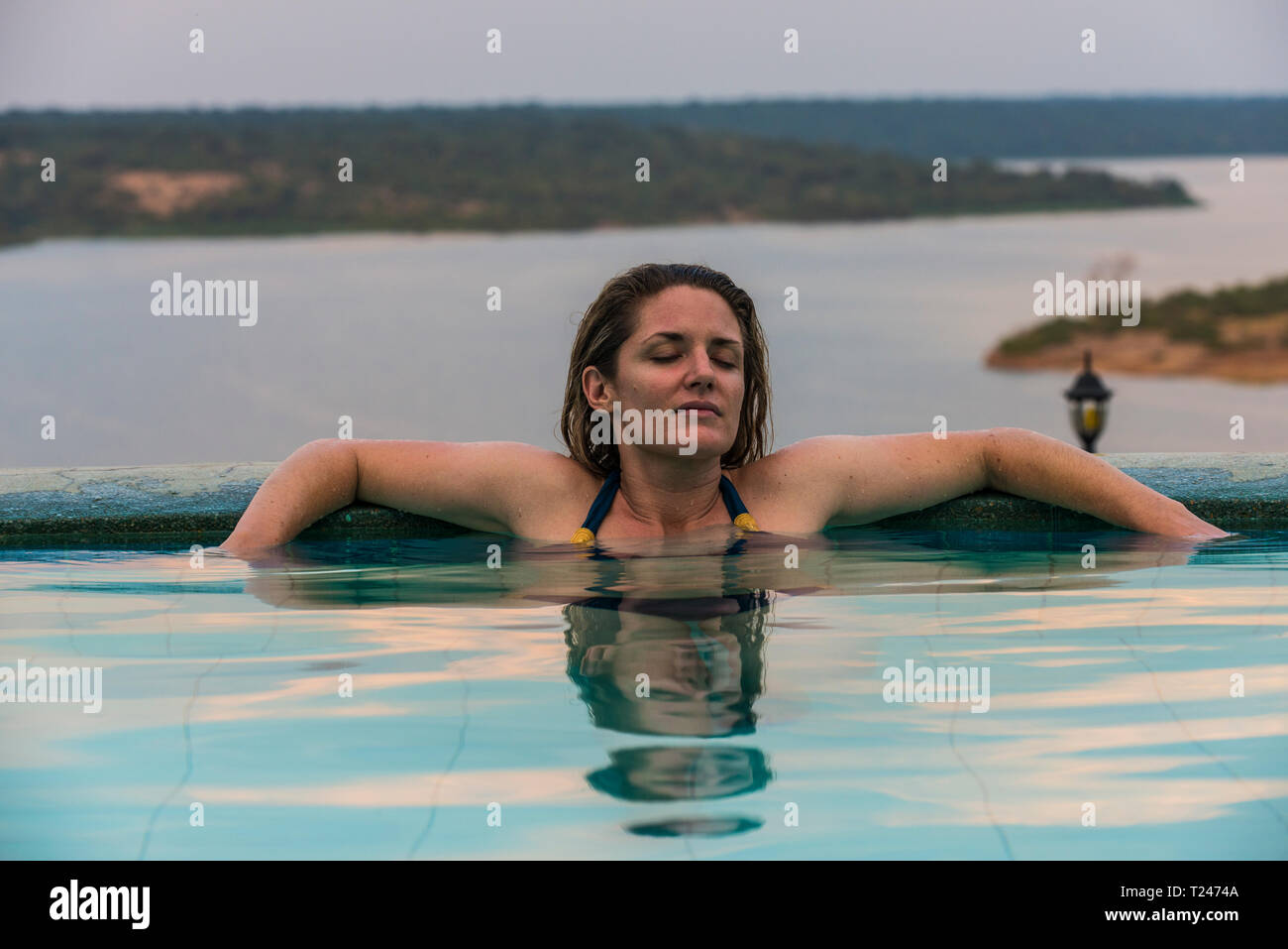 Africa, Uganda, Queen Elizabeth National Park, Donna rilassante in una piscina sopra il canale Kazinga Foto Stock