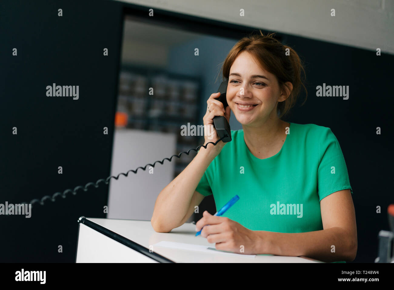 Donna sorridente parlando al cellulare in ufficio Foto Stock