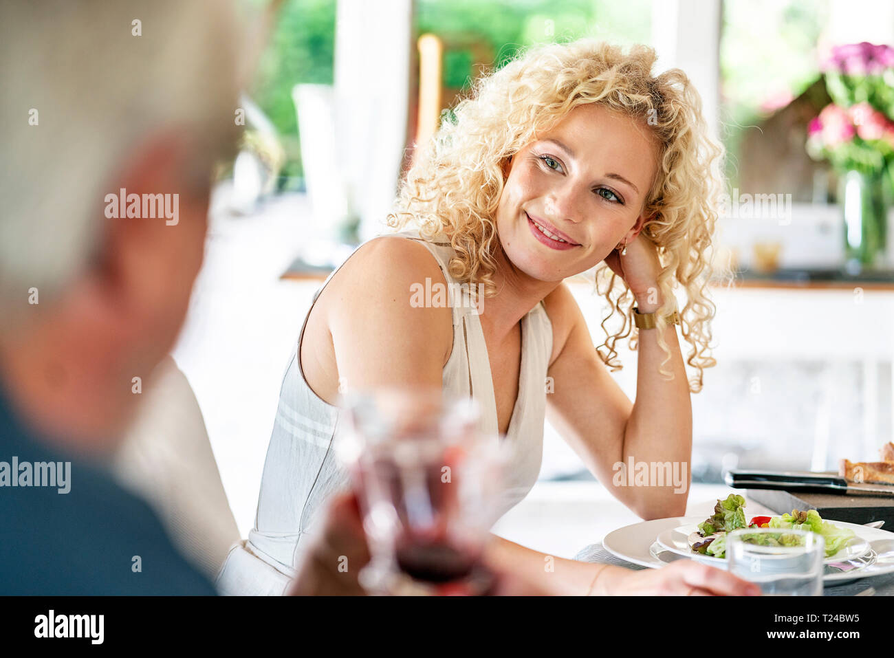 Sorridente giovane donna avente pasto con la famiglia Foto Stock