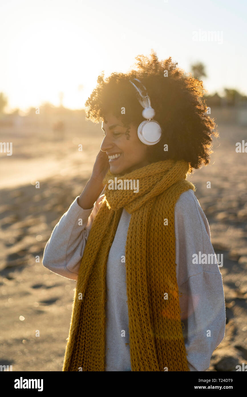 Donna con foulard giallo, ascolto di musica in spiaggia Foto Stock