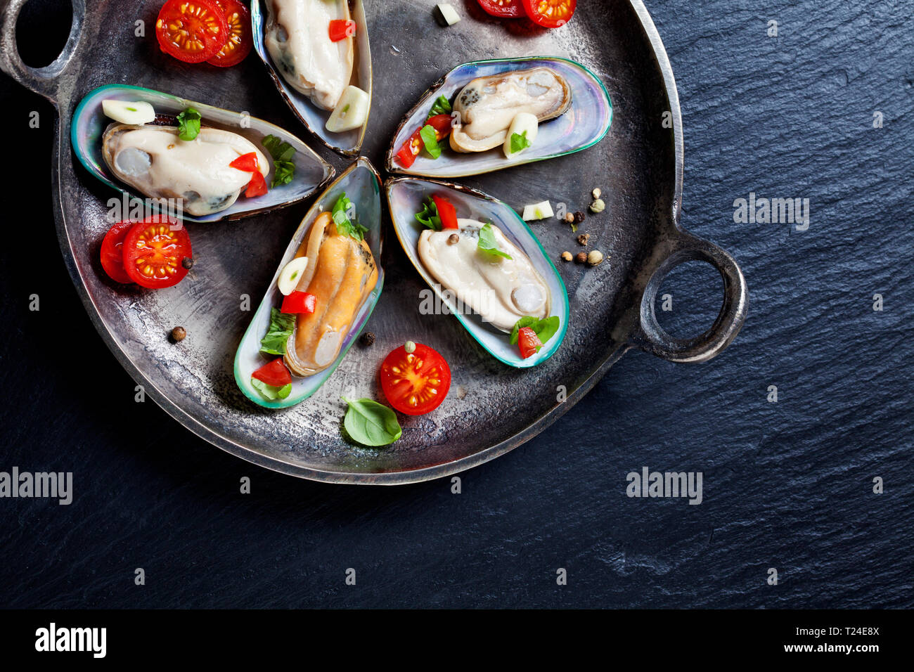 Green le cozze con pomodori, peperoni e aglio in padella di ferro Foto Stock