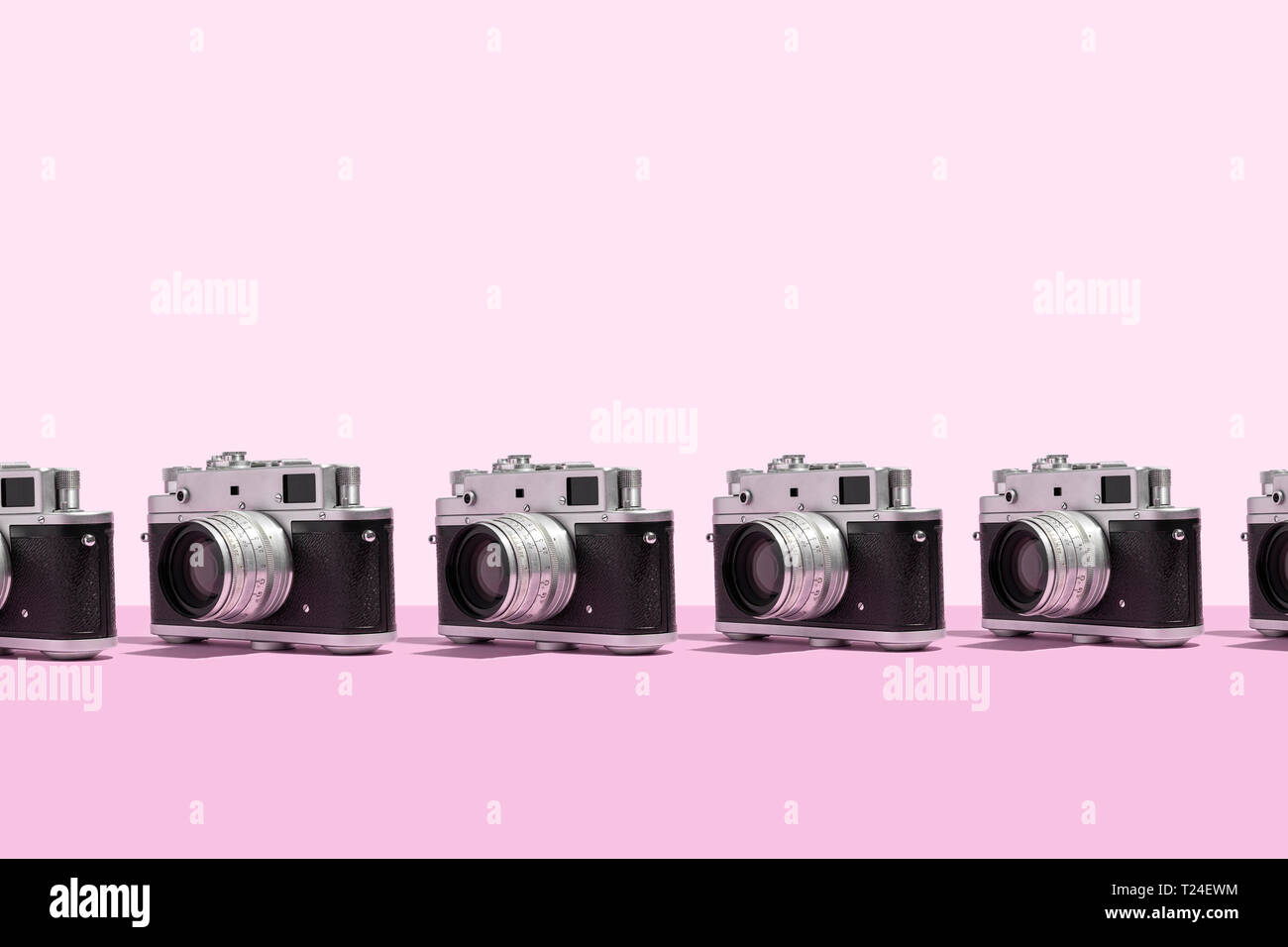Le macchine fotografiche organizzate in una fila su sfondo rosa Foto Stock