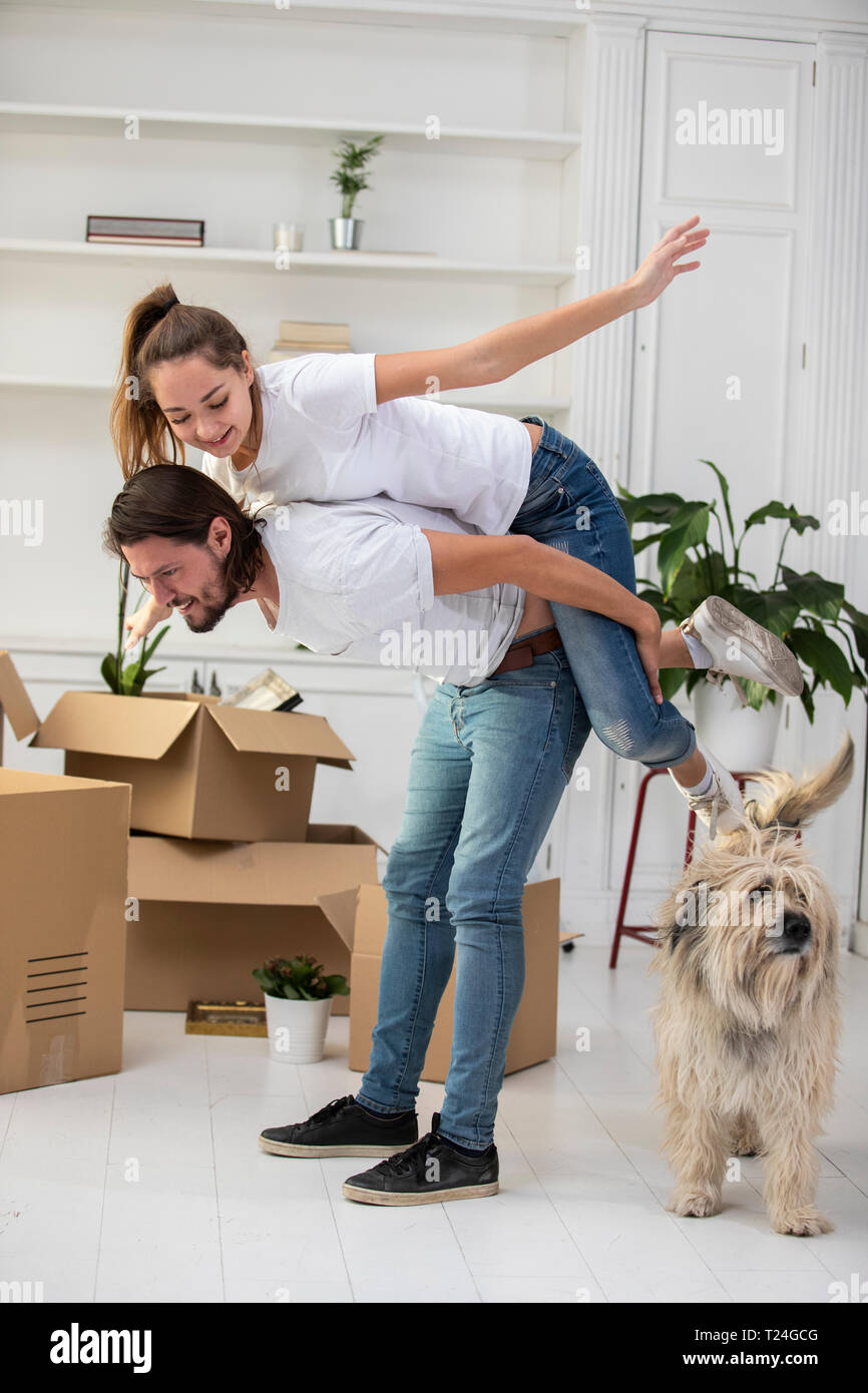 Coppia felice con il cane e scatole di cartone nella nuova casa Foto Stock