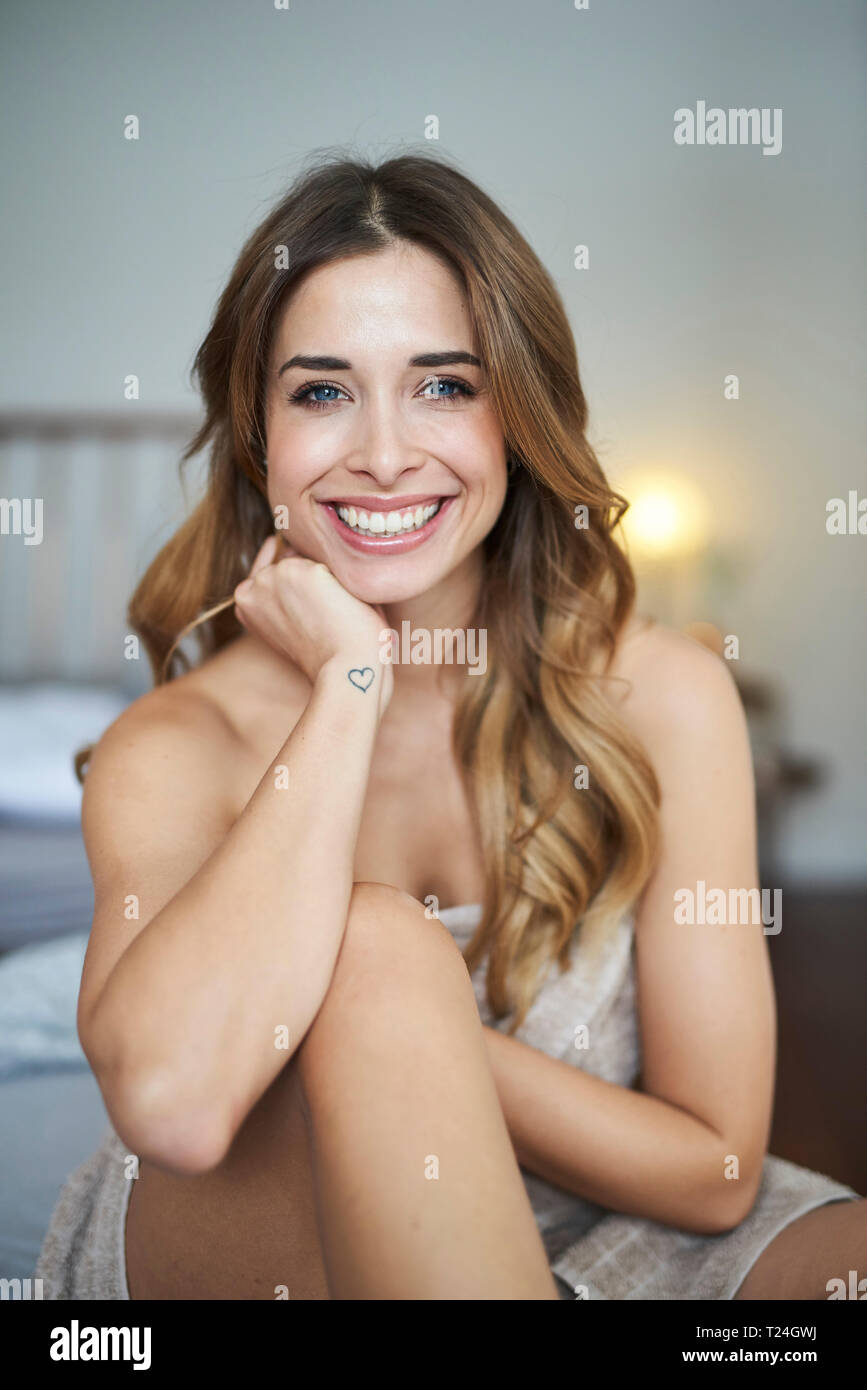 Ritratto di felice giovane donna seduta sul letto Foto Stock