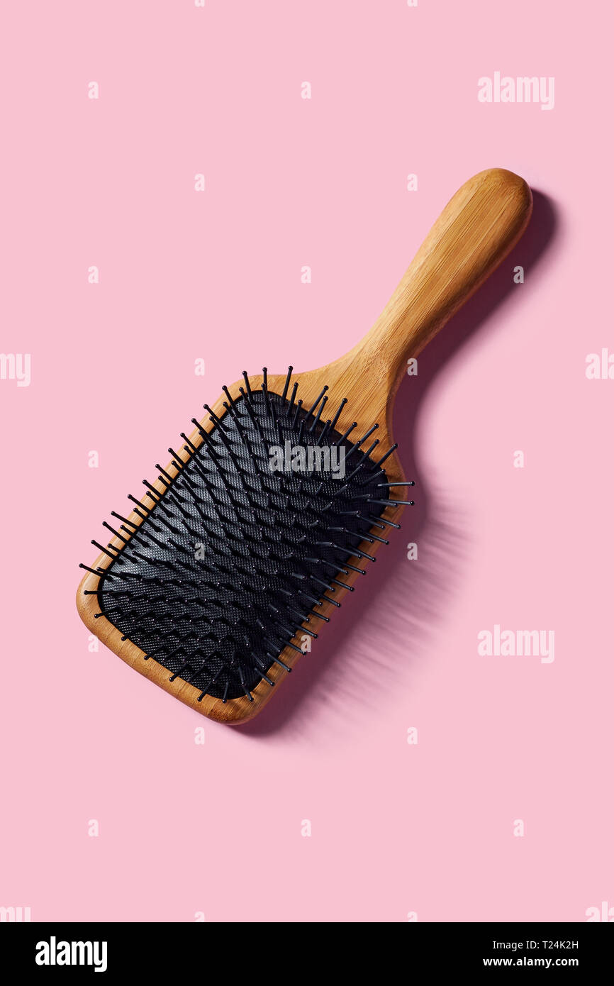 Il bambù racchetta della spazzola per capelli su sfondo rosa Foto Stock