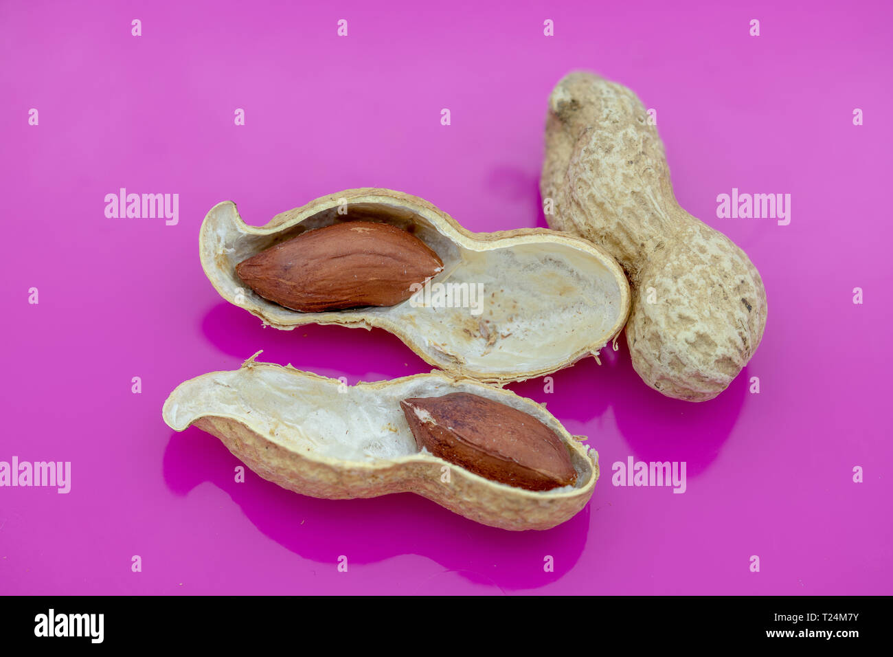 Un intero e split peanut su uno sfondo rosa Foto Stock