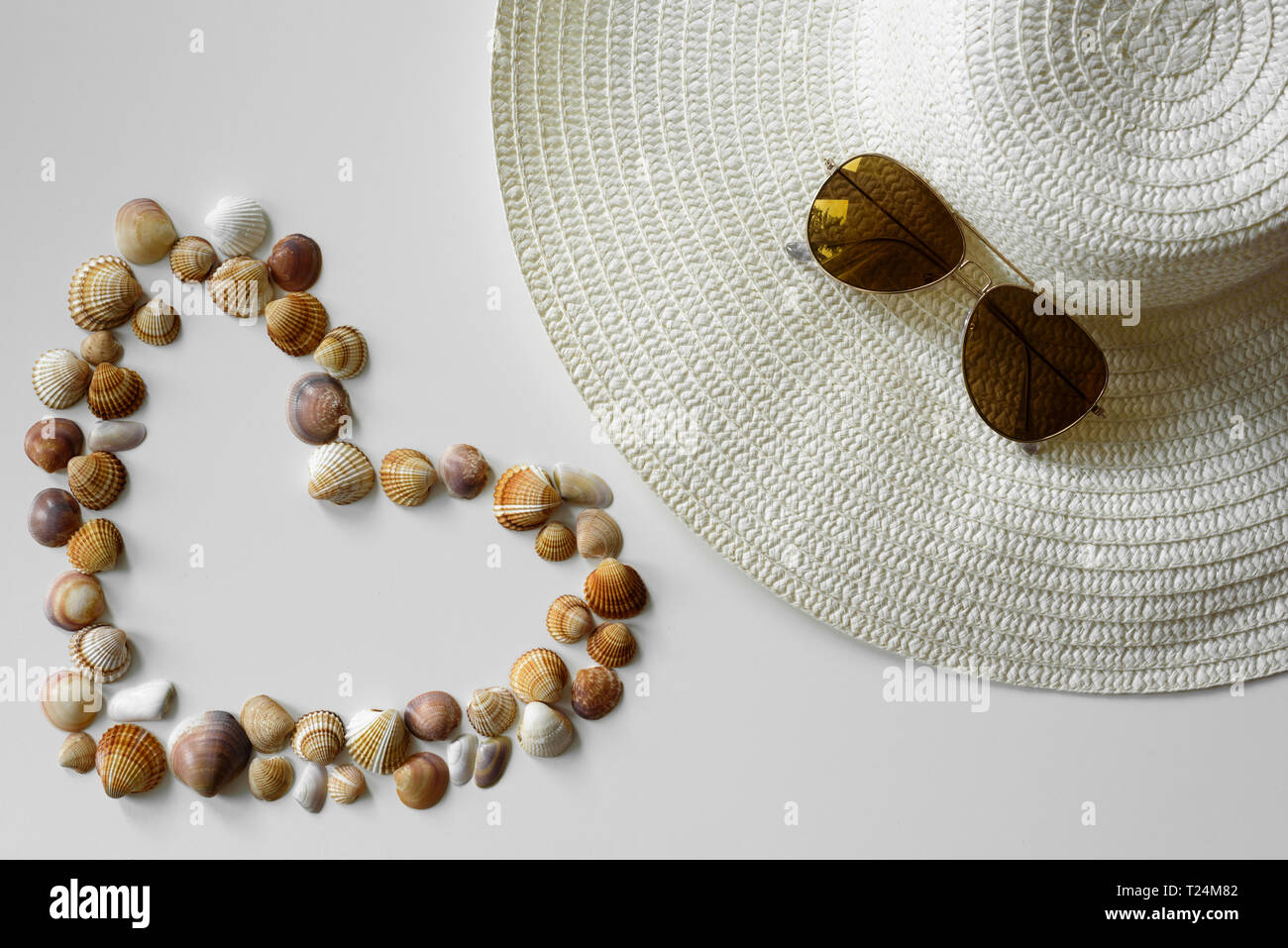 Moda estate disposizione realizzata dall'estate cappello di paglia, aviatore occhiali da sole e conchiglie da beach resort. Foto Stock