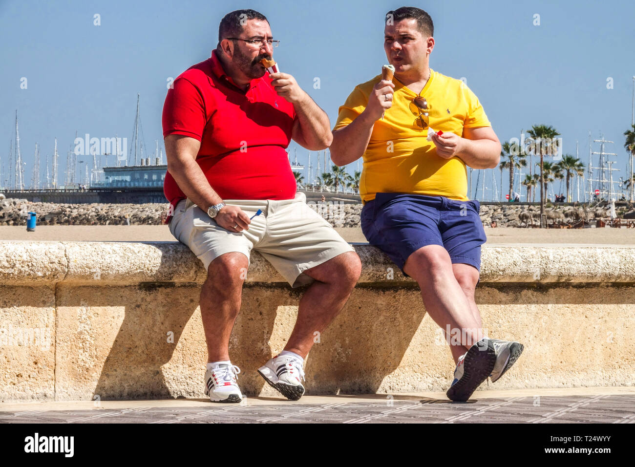 Due uomini che mangiano gelato, Valencia Malvarrosa spiaggia, Spagna Valencia spiaggia turisti, uomo spiaggia di ghiaccio Spagna gelato Foto Stock
