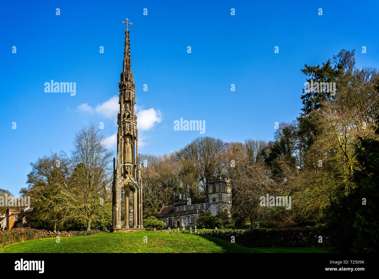 Bristol alta croce spostata a Stourhead nel 1765 medievale con la chiesa di St Peters presi in Stourton, Wiltshire, Regno Unito il 28 marzo 2019 Foto Stock