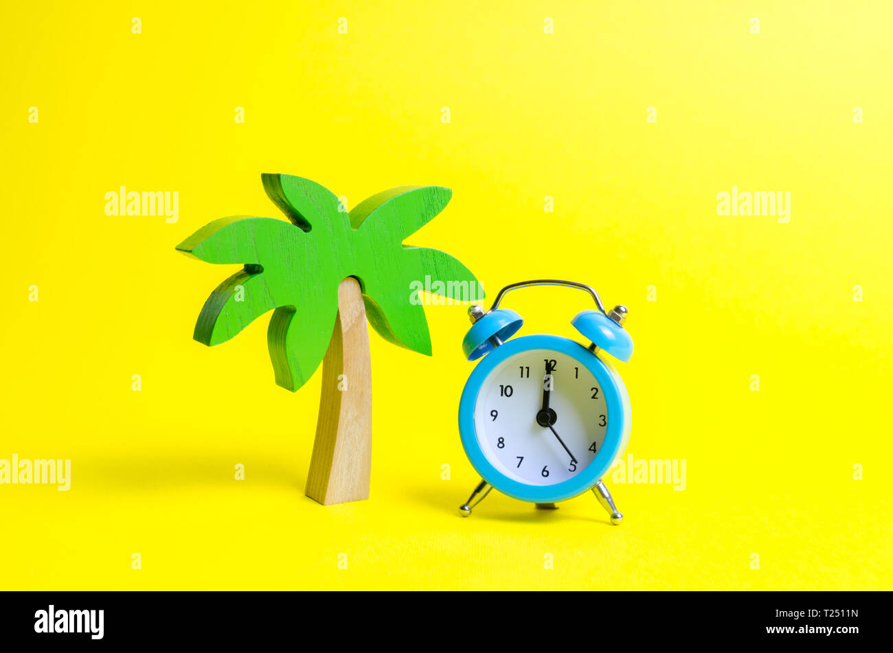 Palm Tree e il blu sveglia su uno sfondo giallo. Tempo per il riposo e il relax. Viaggi, vacanze, crociera. Turismo, la differenza di ore. Limitare Foto Stock