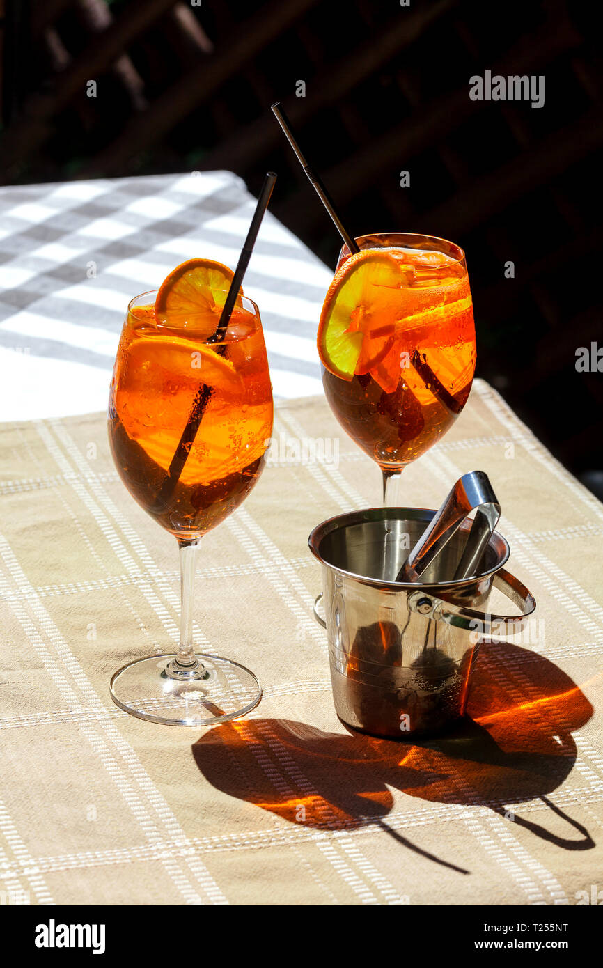 Aperol spritz cocktail in vetro sul tavolo di legno. Due bicchieri con un  cocktail e un secchiello per il ghiaccio sul tavolo con ombra Foto stock -  Alamy