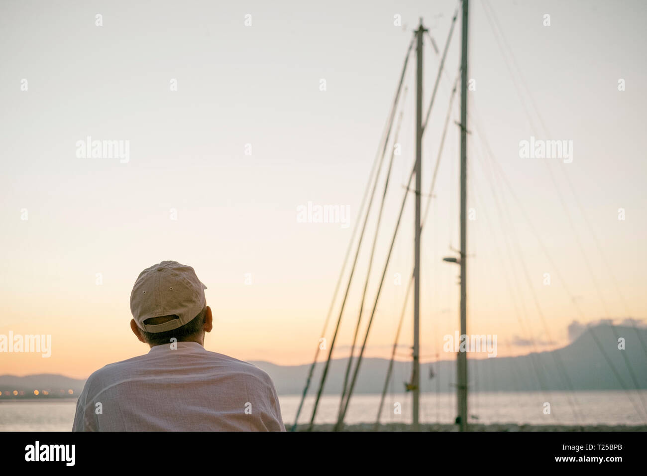 Uomo che guarda il tramonto attraverso le mast Foto Stock