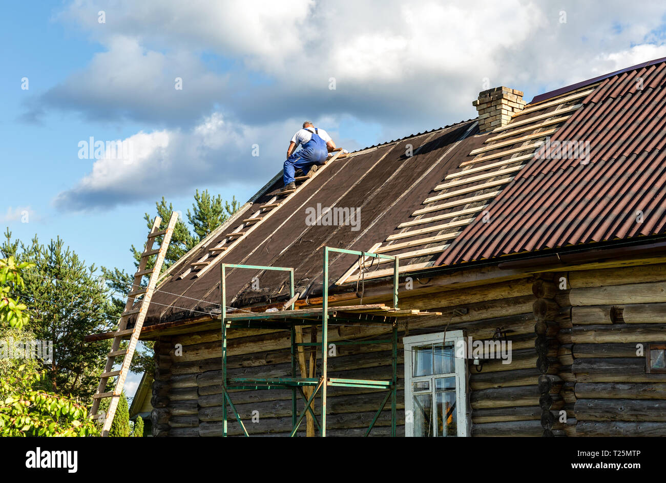 Novgorod, Russia - Agosto 22, 2018: lavoratore le riparazioni sul tetto di una casa in legno nel villaggio Foto Stock