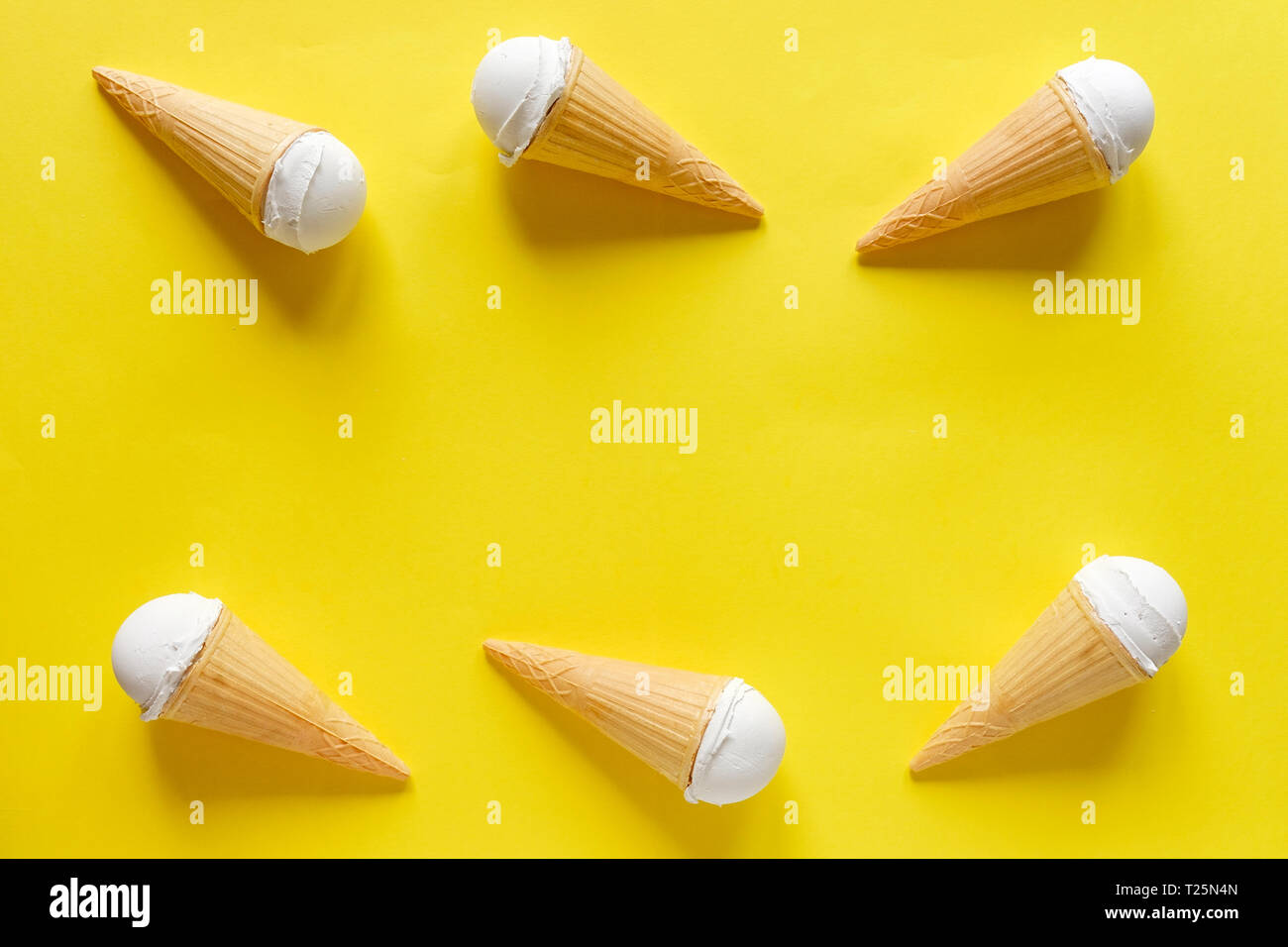 Il doppio bordo laterale di vaniglia coni gelato in un colorato sfondo giallo con copia centrale spazio per estate concetti a tema Foto Stock