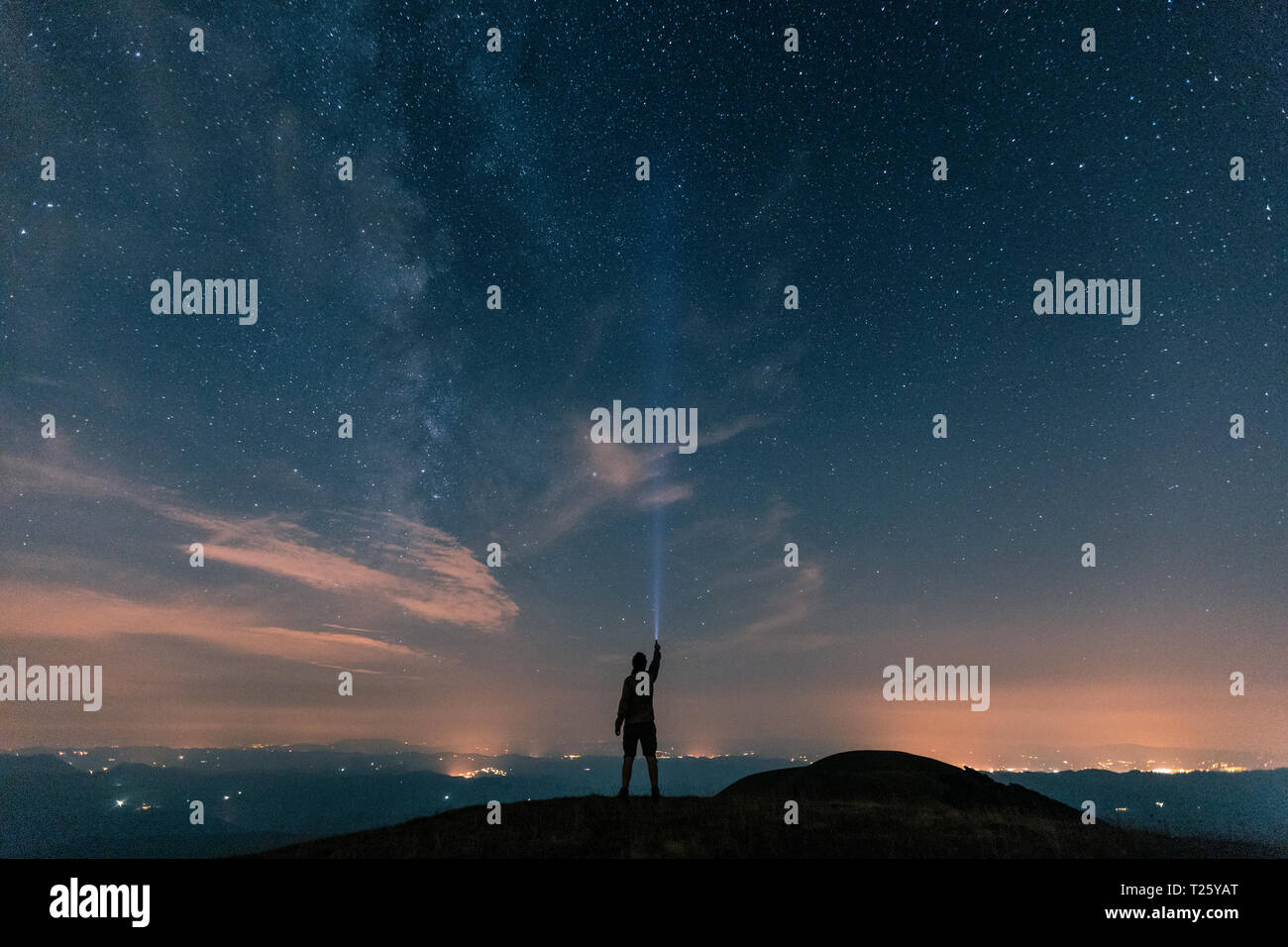 L'Italia, Monte Nerone, silhouette di un uomo con torcia sotto il cielo notturno con le stelle e la via lattea Foto Stock