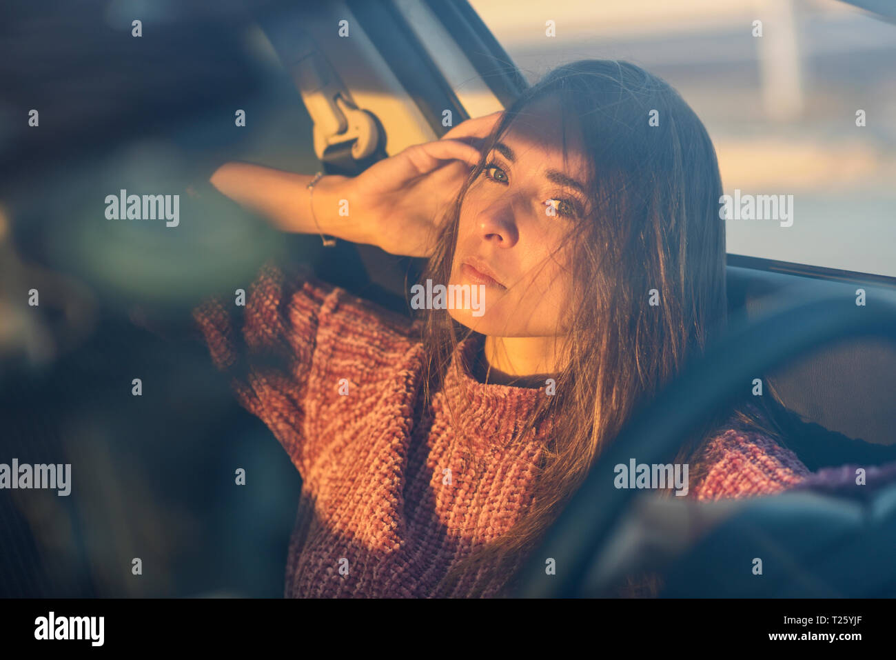 Ritratto di grave donna seduta in auto al tramonto Foto Stock