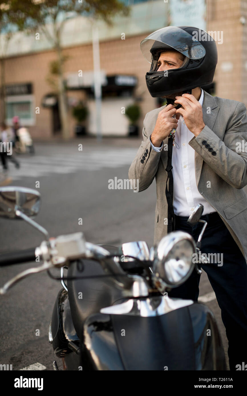 Imprenditore accanto a scooter mettendo sul casco Foto Stock